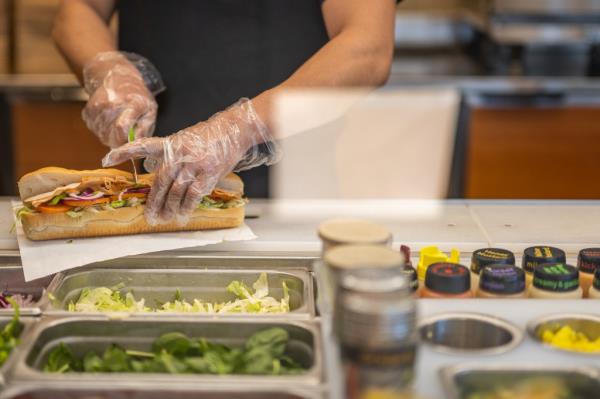 Photo of someone making a sandwich at Subway. 