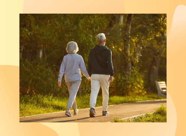 back view of mature couple walking on pathway outdoors for exercise