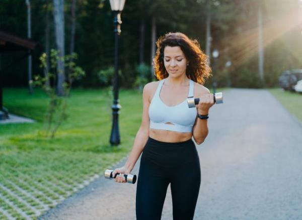 woman walks outside with dumbbells