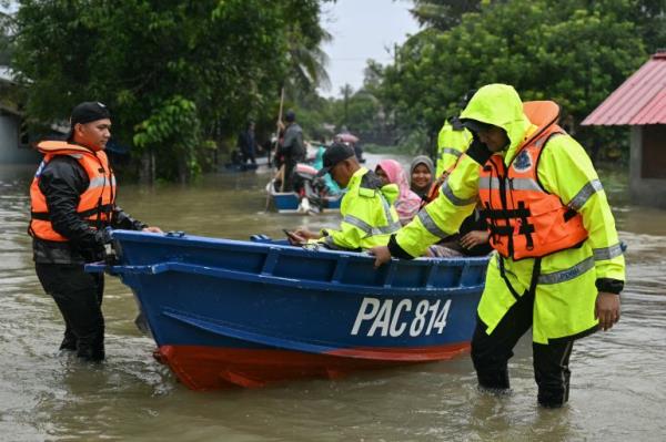 Malaysian police transport residents on a boat through flood waters after days of heavy rain in Tumpat