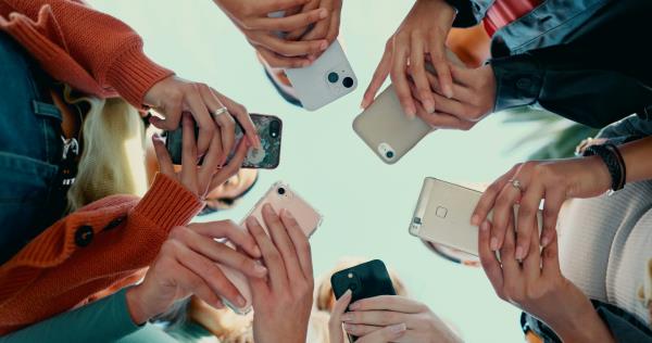 View from below fo a circle of young people looking at their mobile phones