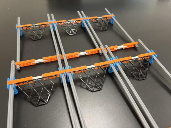 Six different trapezoidal lattices of triangles rest on a table, affixed to holders.