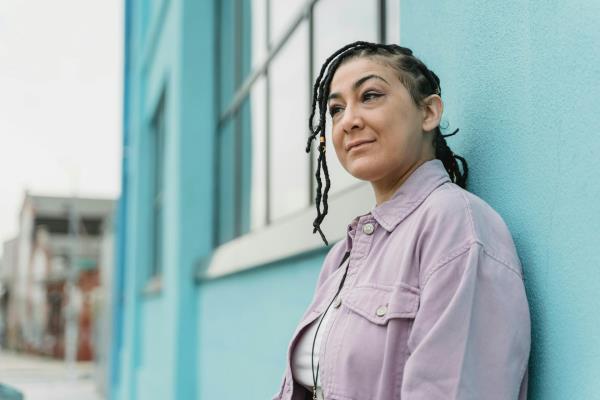 Midlife woman leans against a building