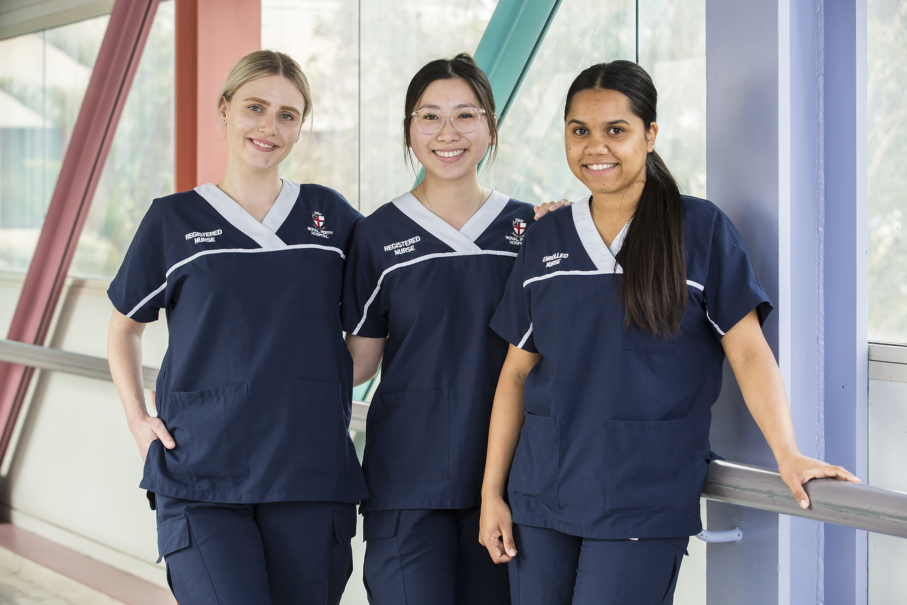 3 Nurses standing in front of a window in a hospital hallway