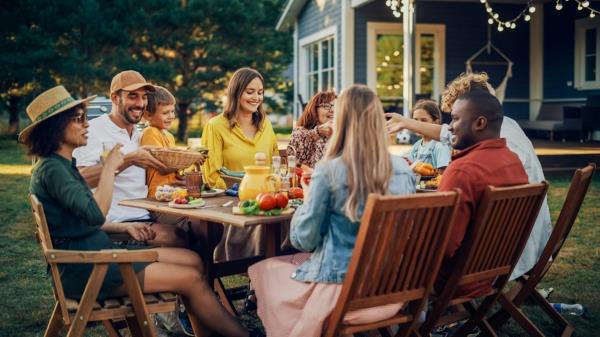 Family and friends around outside table eating and drinking in summer