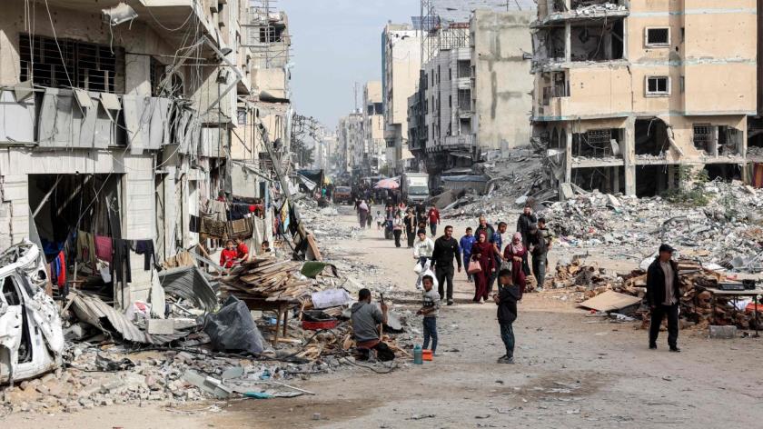 People walk past the rubble of collapsed and damaged buildings along a street in Gaza City, Dec.11, 2024. (AFP Photo)