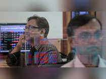 A broker watches a TV news channel as another mo<em></em>nitors share prices at a brokerage firm in Mumbai